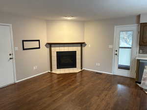 Unfurnished living room featuring dark wood finished floors, a fireplace, and a textured ceiling