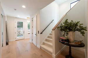 Foyer entrance featuring healthy amount of natural light, light wood-style floors, stairs, and recessed lighting