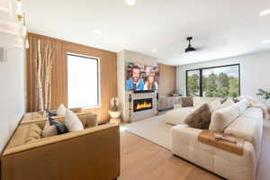 Living room featuring plenty of natural light, wood walls, wood finished floors, a fireplace, and recessed lighting