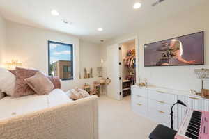 Bedroom featuring a walk in closet, light carpet, and recessed lighting