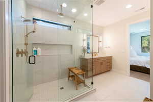 Bathroom featuring healthy amount of natural light, a marble finish shower, vanity, recessed lighting, and connected bathroom