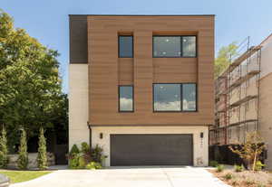 Contemporary home featuring driveway, brick siding, and an attached garage