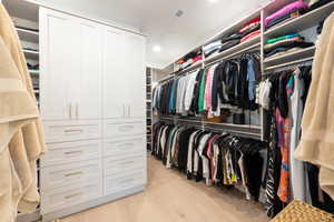Walk in closet with light wood-style flooring