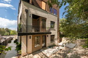 Back of house featuring a balcony and brick siding