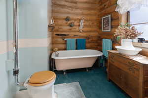 Full bathroom with a freestanding bath, vanity, and rustic walls