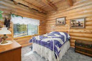 Bedroom with carpet floors, a wood ceiling with exposed beams, and rustic walls