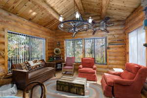 Living room featuring wood ceiling, wood finished floors, log walls, and a chandelier
