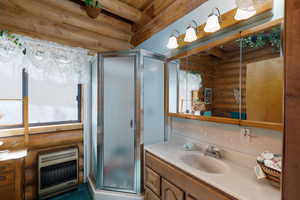 Bathroom featuring log walls, vanity, a shower stall, heating unit, and beam ceiling