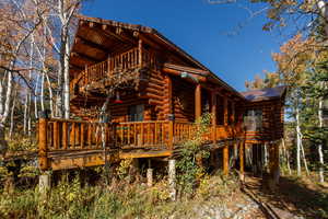 Rear view of property featuring log siding, a deck, and a balcony
