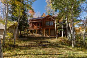 Rear view of house with log exterior, a metal roof, a lawn, and a deck