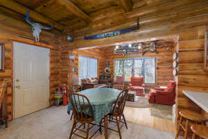 Dining space featuring a wooden ceiling with exposed beams, rustic walls, light wood finished floors, and light colored carpet