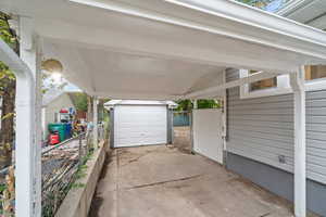 View of covered car port featuring a gate, a garage and driveway