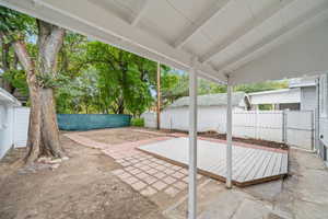 Fenced backyard with a patio area, a gate, a covered deck, and an outbuilding