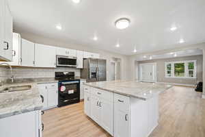 Kitchen featuring appliances with stainless steel finishes, white cabinets, backsplash, open floor plan, and recessed lighting