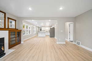 Unfurnished living room with a wood stove, light wood finished floors, arched walkways, and recessed lighting