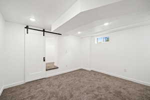 Bedroom with carpet floors, a barn door for storage area, and recessed lighting