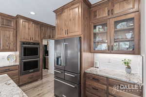 The beautiful custom cabinetry really shows in this photo with the open glass and fridge surround. The pantry door is open in this photo.