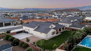Aerial view at dusk of a residential view, a mountain view, and view of the large backyard.
