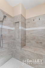 The primary bath features a large walk-in shower with dual shower heads, a built-in seat, and convenient niches for all your essentials.