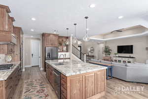 Functional layout with large island, double ovens, has cooktop, black stainless appliances that add to the warmth of this kitchen.