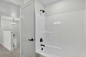 Full bath featuring carpet flooring, tub / shower combination, and a chandelier