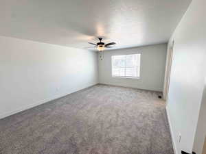 Spare room featuring a textured ceiling, carpet floors, and ceiling fan