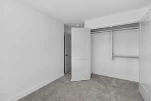 Unfurnished bedroom with light carpet and a closet