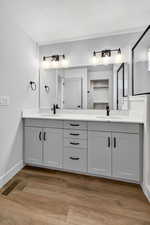 Full bathroom featuring double vanity, light wood-style floors, and a textured ceiling
