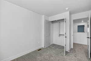 Unfurnished bedroom featuring light colored carpet and a closet