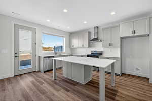Kitchen with a breakfast bar area, decorative backsplash, light wood finished floors, light stone countertops, and wall chimney exhaust hood