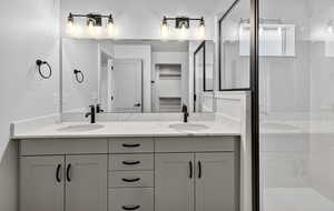 Bathroom featuring double vanity, a marble finish shower, and a spacious closet