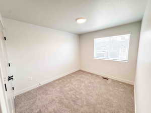Carpeted spare room with a textured ceiling and baseboards