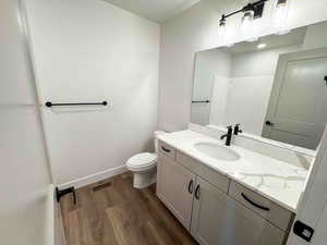 Bathroom with dark wood-style flooring, vanity, and a shower