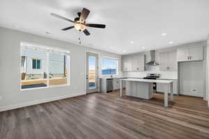 Kitchen with stainless steel appliances, tasteful backsplash, dark wood-style floors, wall chimney exhaust hood, and a kitchen island