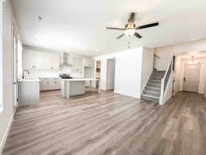 Kitchen featuring open floor plan, a kitchen island, light countertops, white cabinetry, and light wood-style floors