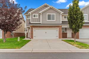 View of front facade with board and batten siding, driveway, a shingled roof, a front lawn, and a garage