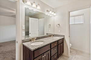 Bathroom  in primary suite featuring double vanity, light tile patterned floors, and a textured ceiling