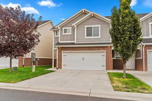 View of front of house with board and batten siding, driveway, brick siding, and a front lawn