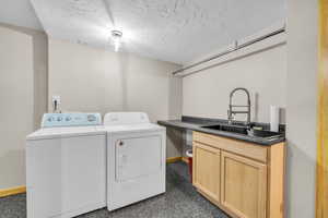 Laundry area featuring a textured ceiling, independent washer and dryer, and cabinet space
