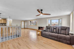 Living area featuring healthy amount of natural light, light wood-style flooring, a ceiling fan, and a chandelier