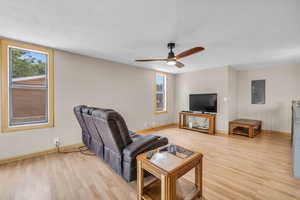 Living area with light wood-style flooring, electric panel, a textured ceiling, and a ceiling fan