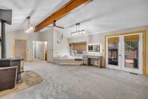 Bathroom featuring a wood stove, carpet floors, a bath, a ceiling fan, and french doors