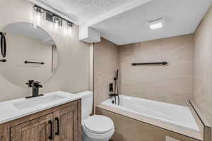Bathroom featuring vanity, a textured ceiling, and tiled shower / bath combo