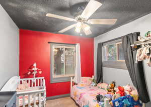 Carpeted bedroom with a ceiling fan and a textured ceiling