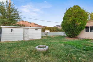View of yard featuring a fire pit, a mountain view, and an outdoor structure