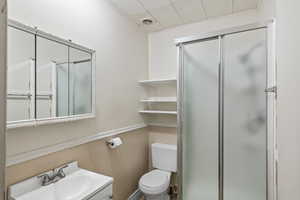Bathroom featuring a shower stall, vanity, and a drop ceiling