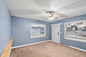 Carpeted foyer entrance with a textured ceiling and ceiling fan