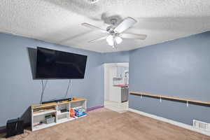 Interior space with light carpet, a textured ceiling, and ceiling fan