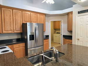 Kitchen with stainless steel fridge with ice dispenser, ceiling fan, electric stove, separate Entrance to Laundry Room and Garage and dark  countertops