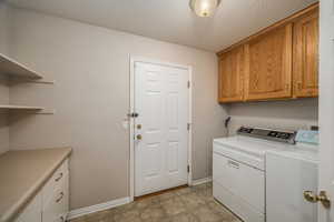 Laundry room with cabinet space, a textured ceiling, and washing machine and clothes dryer